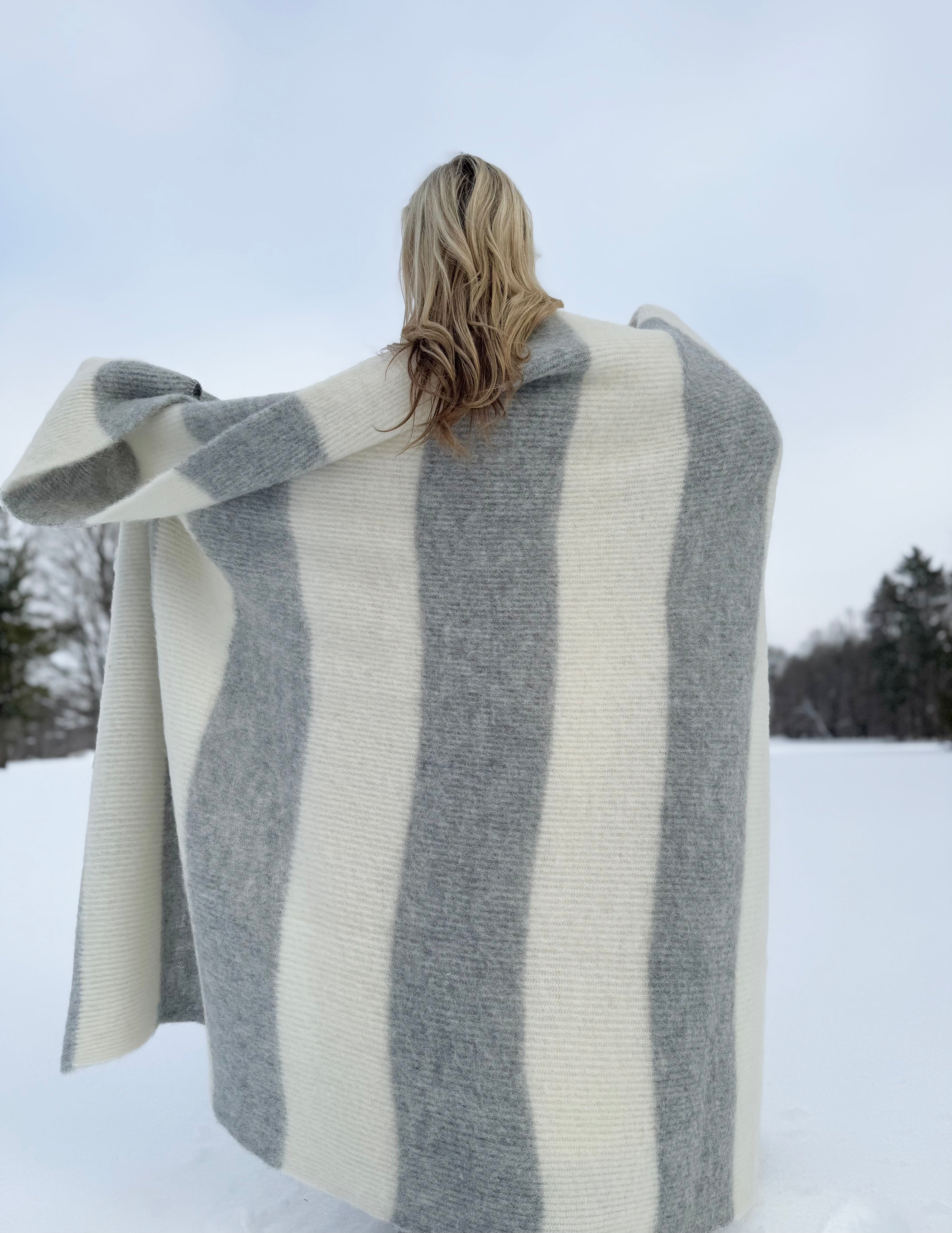 Person wearing a large striped scarf in a snowy landscape